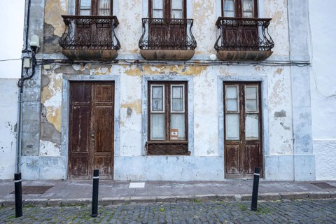 Weathered façade of an empty house in Garachico, characterized by crumbling plaster, old wooden