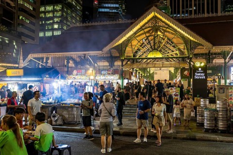 Crowds gather at Satay Street night market beside the Victorian cast iron Lau Pa Sat market