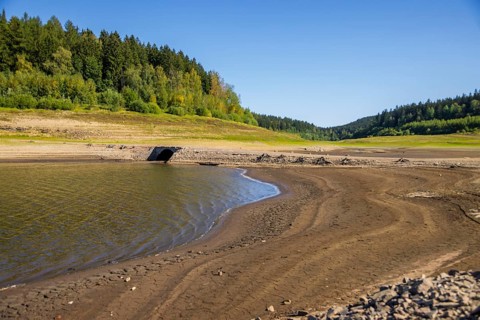 A historic arched bridge appears through low water in the Lehnmühle dam, Dippoldiswalde, Saxony,