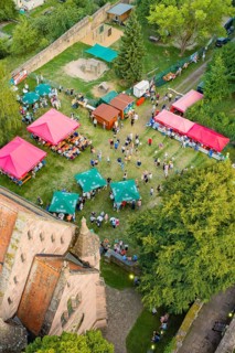 Summer party with colorful tents and lots of people on a green area surrounded by trees, Calwer