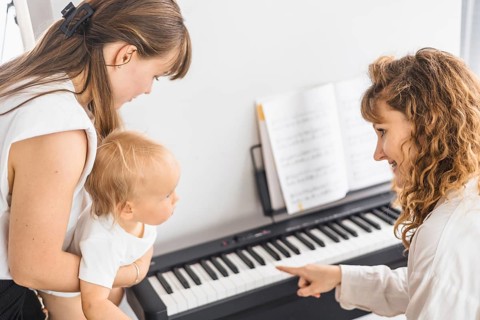 A mother and child interact at a piano, focusing on a shared learning moment