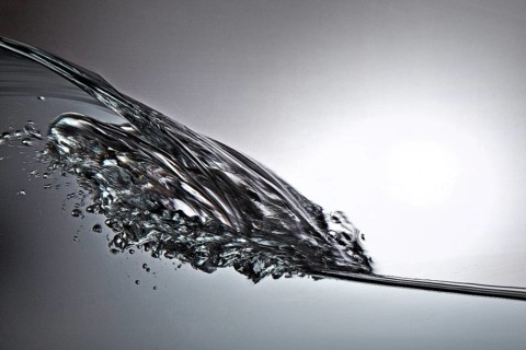 A small longitudinal wave frozen by short exposure in crystal-clear water in the photo studio