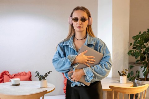 Young Caucasian woman with long blonde hair, wearing sunglasses and a denim jacket, holding a