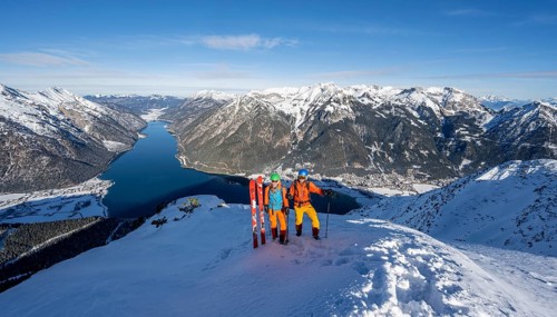 Picturesque view of Achensee and wintry mountain scenery, ski tourers, couple at the summit of