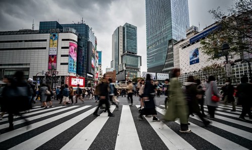 Crowd crossing zebra crossing on a large intersection, motion blur, back modern houses with