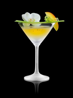 Yellow cocktail in an iced martini glass, orchid blossom and apricot wedge as garnish, against a