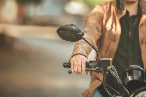 Hands of male motorcyclist on the handlebars on the road. Hands of moto biker on the handlebars of