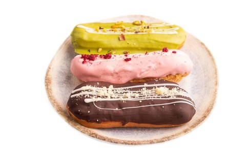 Glazed Eclairs on brown concrete isolated on white, side view, close up