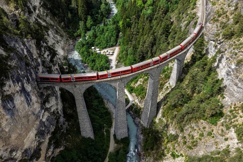 Red train of the Rhaetian railroad line, Bernina Express, passing the Landwasser Viaduct, arch