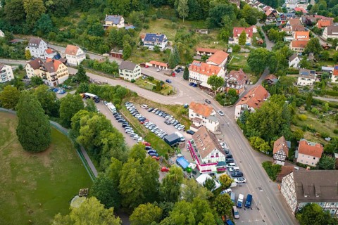 Aerial view of a village with roads, parked cars and surrounding green landscape, Calwer