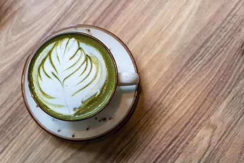 A cup of matcha latte on the table. Latte art on a green background, A matcha latte with leaf