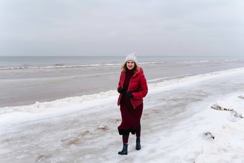 Winter walk along the sea, a woman walks and smiles, A woman in a red coat and hat walks on a snowy