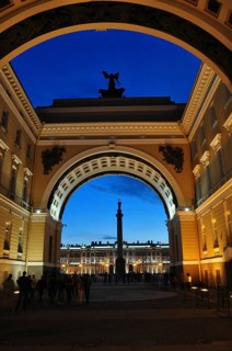Huge archway with sculptures inside, overlooking illuminated buildings, General Staff Building,