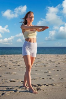 Beach scene featuring a woman, yoga, tadasana, mountain pose, practicing yoga, and arm extension