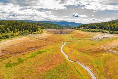Wide view of a valley with a dam and a winding river, rehabilitation of the Schwarzenbach dam,