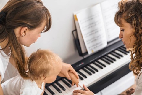 A mother and child share a bonding activity at the piano, focusing on guidance