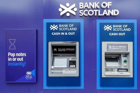 Bank of Scotland automated teller machines offering cash in and cash out services on a street wall