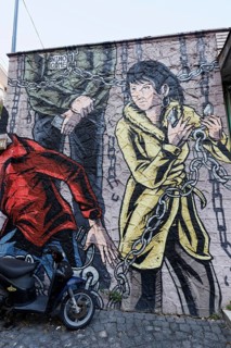 Young woman frees herself from chains wall painting street art artist Nino Come, Rione Sanità,