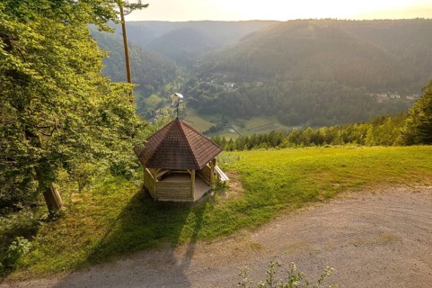 A pavilion with a view of a picturesque valley, surrounded by forests in the evening light,
