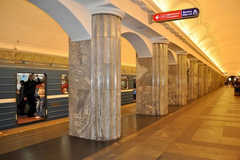 Well-lit subway station with massive marble columns and a blue train, metro, Saint Petersburg, St.