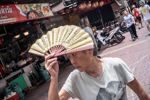 Bangkok, Thailand. August 24th 2026. An elderly lady shields her face from the sun during August