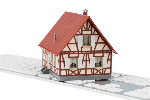 Residential building on keyboard, symbolic photo for buying and renting a house via the Internet