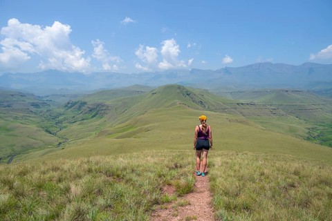 Green hills and valleys, young woman hiking through landscape, Worlds View Hike, Drakensberg, South