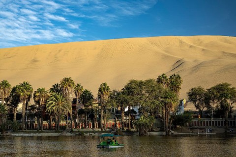 The oasis, Laguna Huacachina with a small lake and palm trees surrounded by sand dunes in the Ica