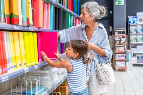 Grandmother and granddaughter perusing a bright stationery aisle, searching for school organization