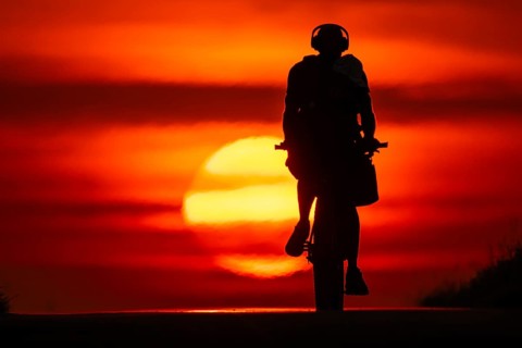 A cyclist rides towards the rising sun on a dirt road near Frankfurt am Main, Frankfurt am Main,