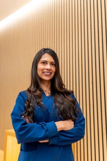 Hispanic professional woman wearing blue scrubs, confidently smiling with arms crossed, standing
