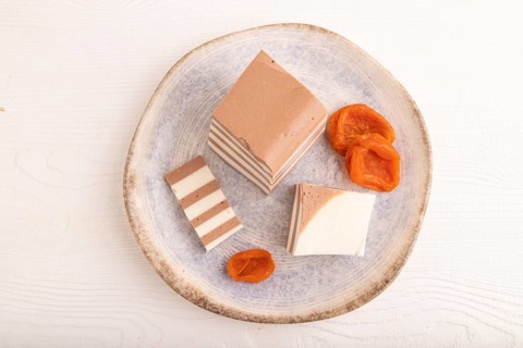 Cocoa and milk jelly with dried apricots on white wooden background, top view, flat lay, copy