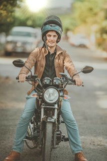 Portrait of Latin motobiker on his motorcycle on the asphalt. Portrait of smiling male motorcyclist