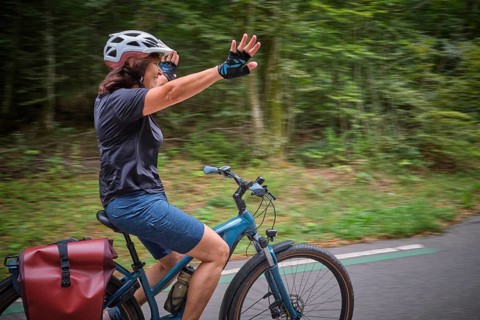 Active senior woman having fun practicing handsfree cycling on a bike path through a peaceful