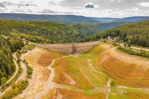 Dam in an autumnal mountain landscape, surrounded by extensive forest areas, rehabilitation of the