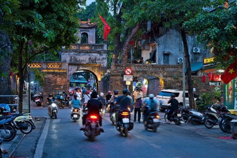 City gate during the evening rush hour on a busy street with mopeds, scooters, motorbikes and