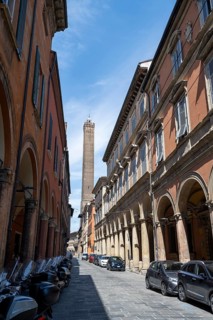 Portici arcades and historic buildings in Strada Maggiore, behind Asinelli Tower of Due Torri, old