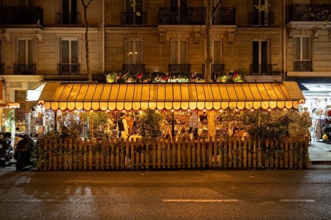 Nocturnal, summer street scene in front of a traditional French bistro, outdoor dining, with guests