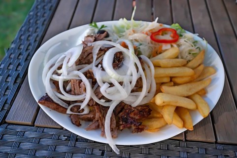 Giros served with French fries and raw onion rings in a Greek garden restaurant, Franconia,