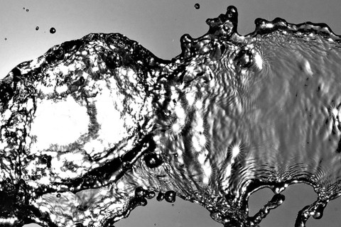 Water frozen by short exposure moving in backlight in front of the sun