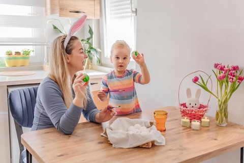 Mother and little daughter painting Easter eggs at home. family tradition, spring celebration and