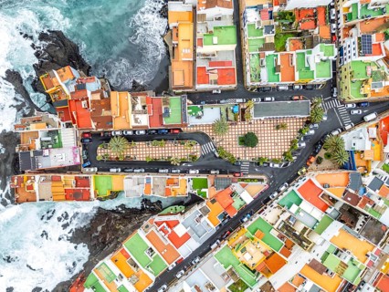Aerial view from above wild waves in the Atlantic with colorful houses on the island of Tenerife by