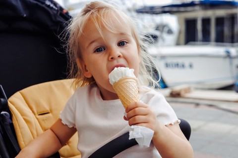 Young girl eating ice cream at a port on a sunny summer day in Fethiye marina, Turkiye