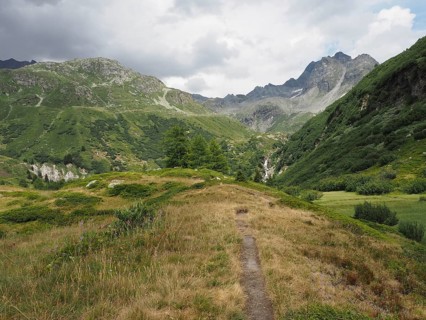 Quiet mountain landscape in summer with green hills and clouds in the sky, hiking trail leads