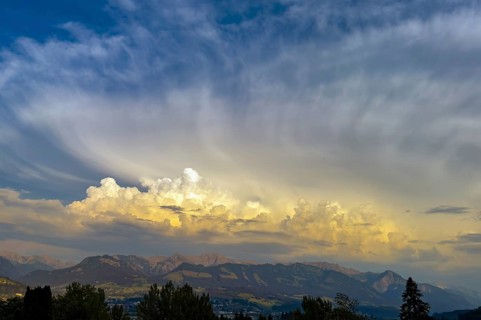 Yellowish cloud front with cumulus cluster wokes pile up over the edge of the Alps with high