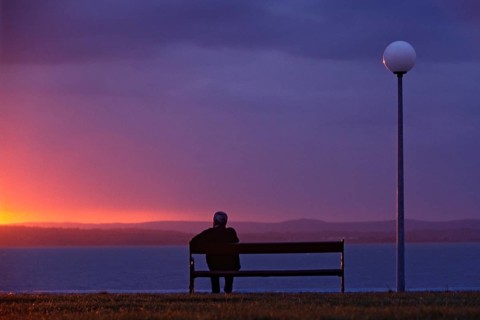 Europe, Greece, Crete, man sitting on bench looking at the sea, sunset, Men sit on a bank and take