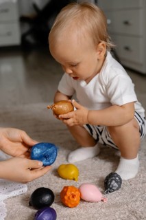 A toddler explores colorful toys with curiosity, emphasizing learning and playful focus in an