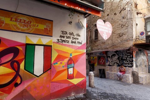Bar on a street corner with painted Aperol advertising, street art in Quartieri Spagnoli, Spanish