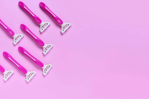 Pink women's disposable razors arranged on pastel background for shaving, skincare and beauty