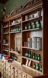 Mortar, glass apothecary bottles, apothecary scales, vessels on a shelf, the Svaneapoteket (Swan